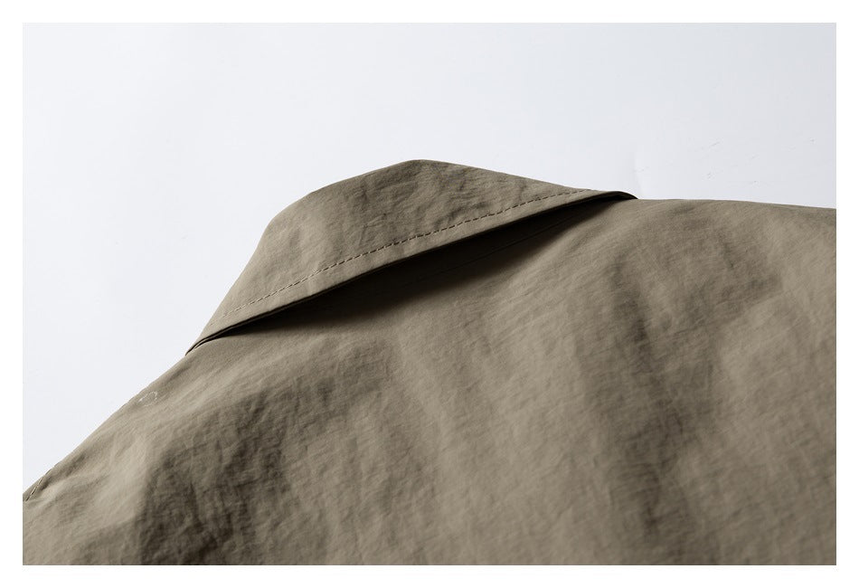 Close-up of a pointed collar and wrinkled taupe fabric on a garment.