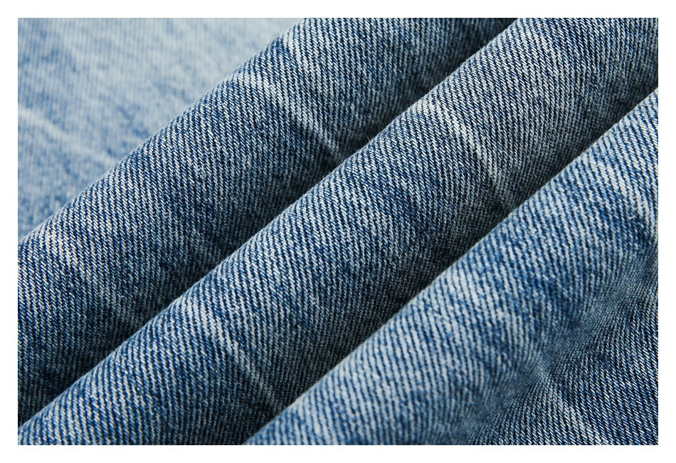 Macro view of blue denim folded into ridges, showing the diagonal twill weave.
