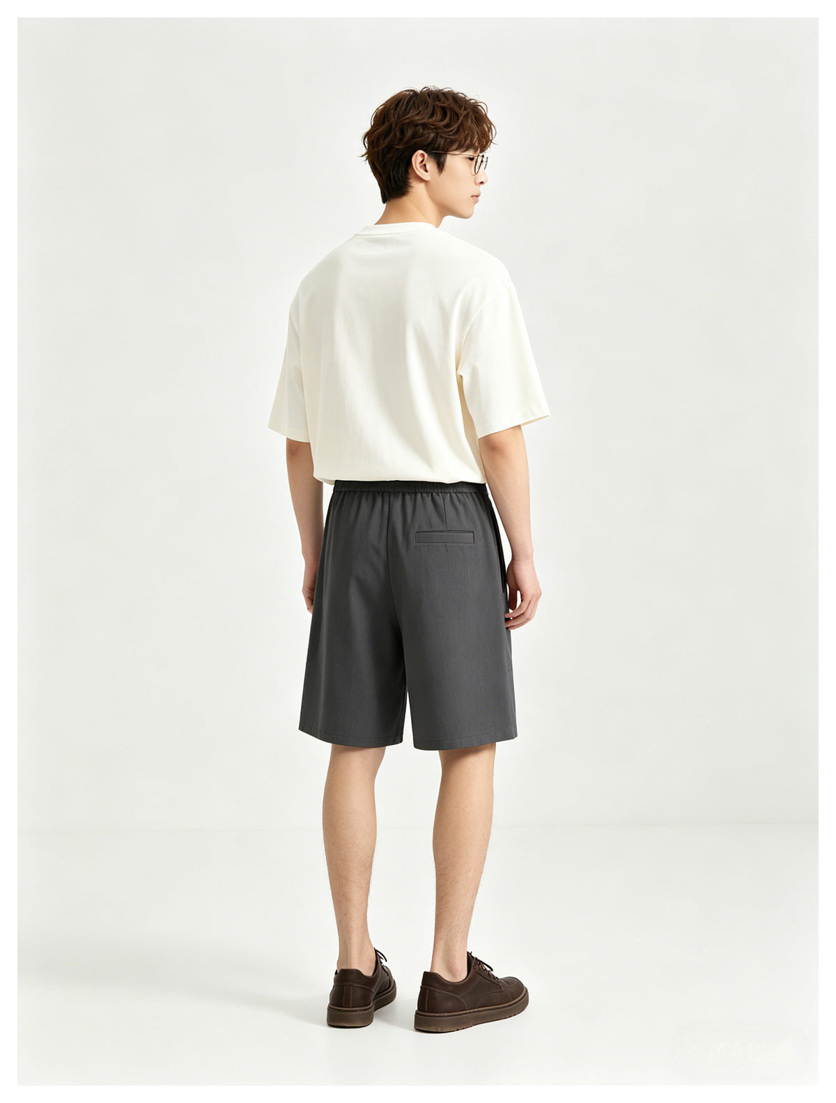 Model wearing a white T-shirt and charcoal shorts, shown from the back.