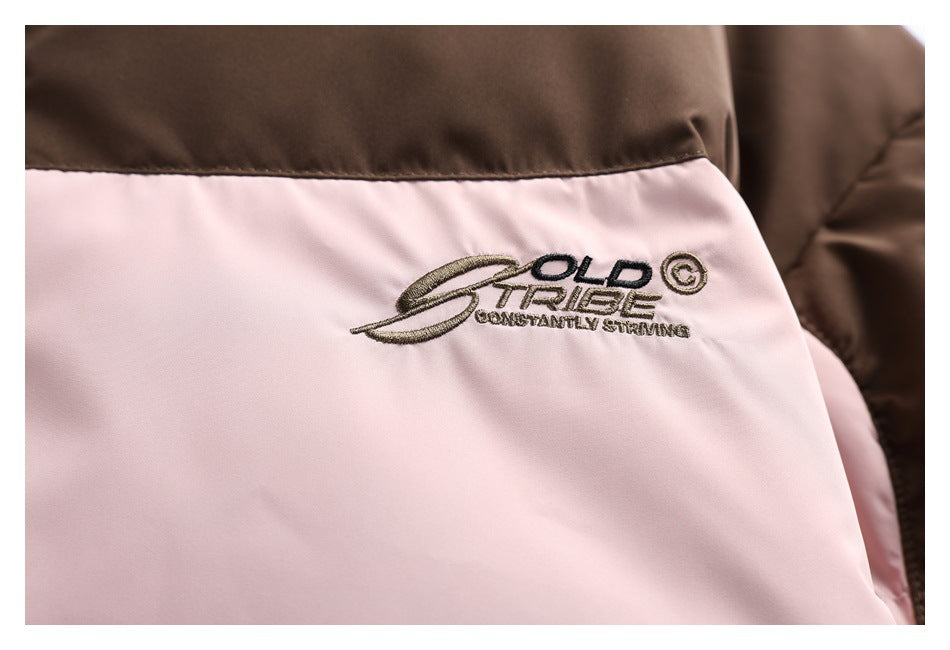 Close-up of the jacket's embroidered English chest logo on pale pink fabric below a brown panel.