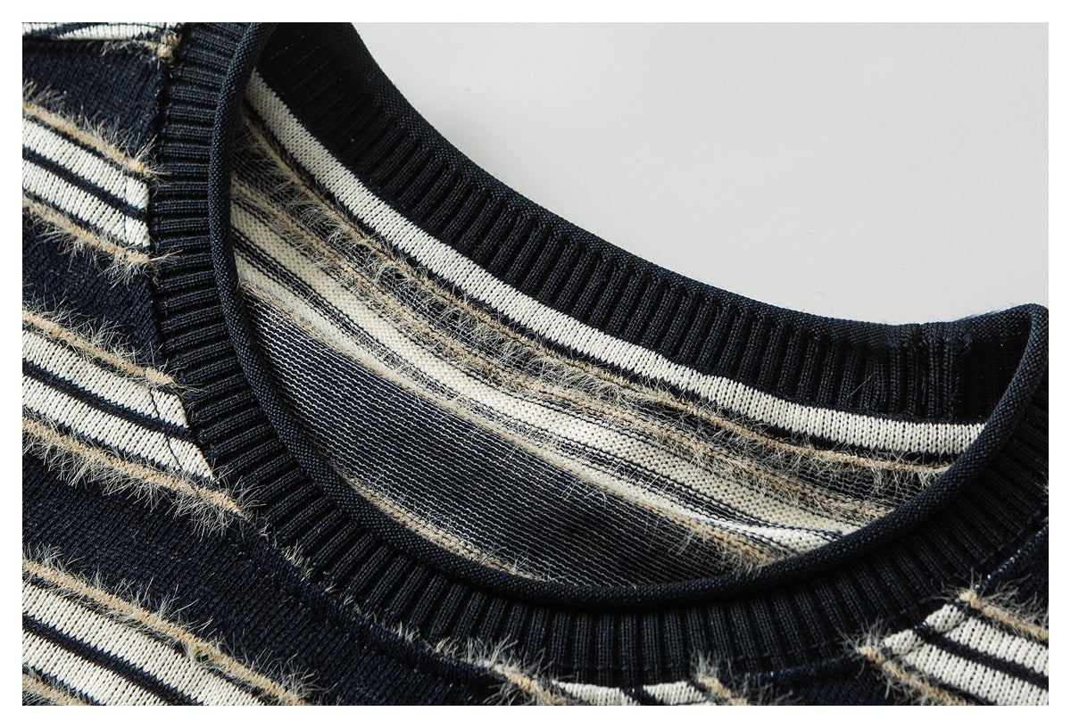 Close-up of a navy knit sweater’s ribbed crew neckline and cream stripes with fuzzy beige accents.