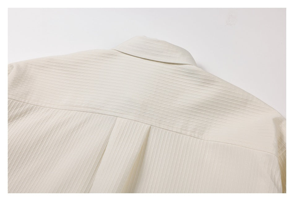 Close-up of the ivory shirt's back collar, yoke seam, and center pleat.