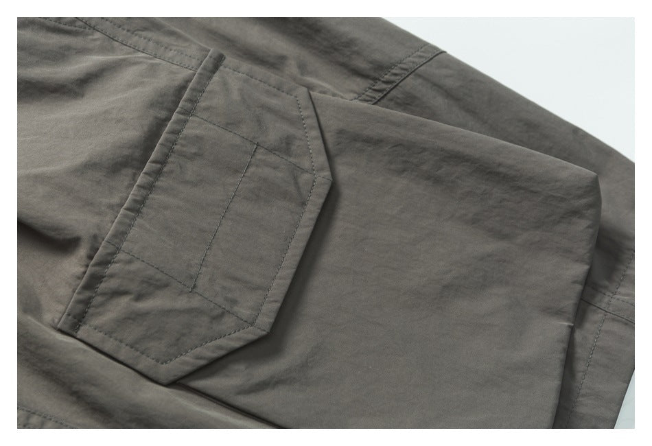 Close-up of a stitched flap pocket on charcoal-gray trousers.