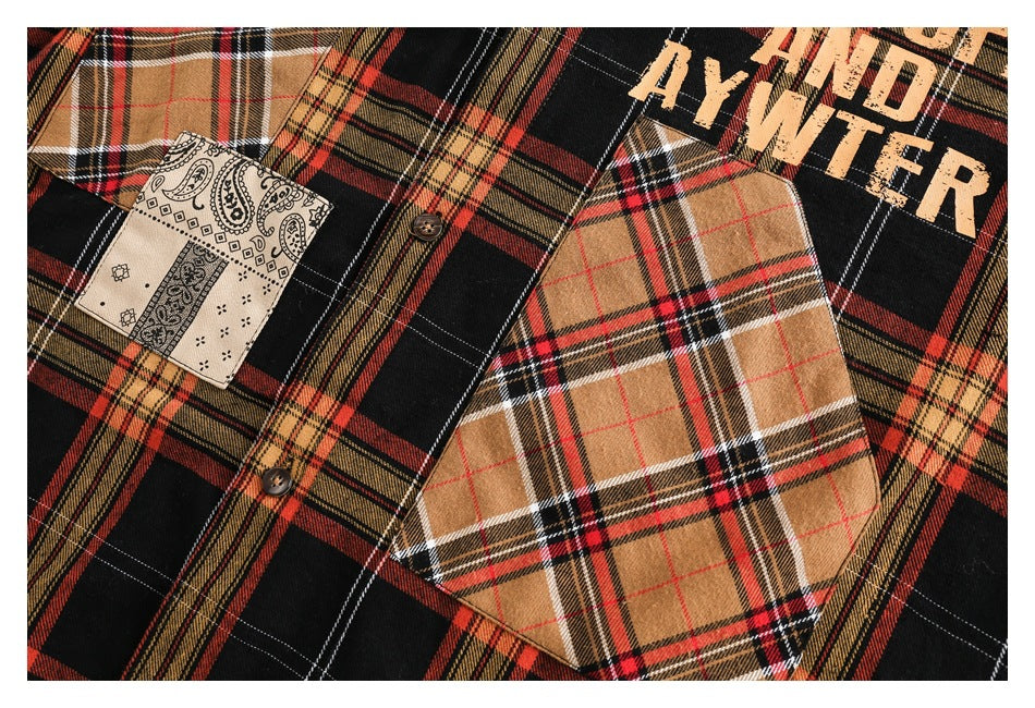 Close-up of a tan plaid chest pocket, paisley patch, buttons and lettering on a black and red plaid shirt.