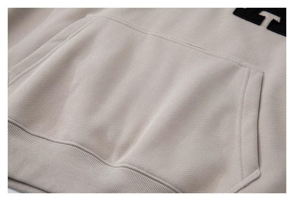 Close-up of the taupe sweatshirt's kangaroo pocket and stitched edges.