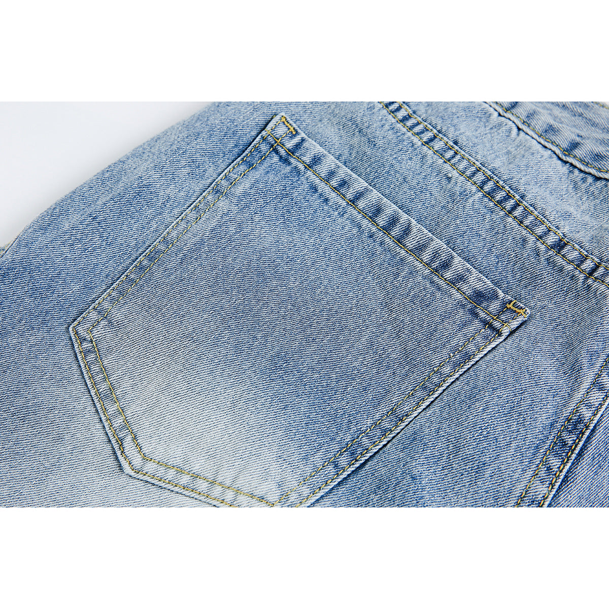 Close-up of a stitched back pocket on light blue denim shorts.