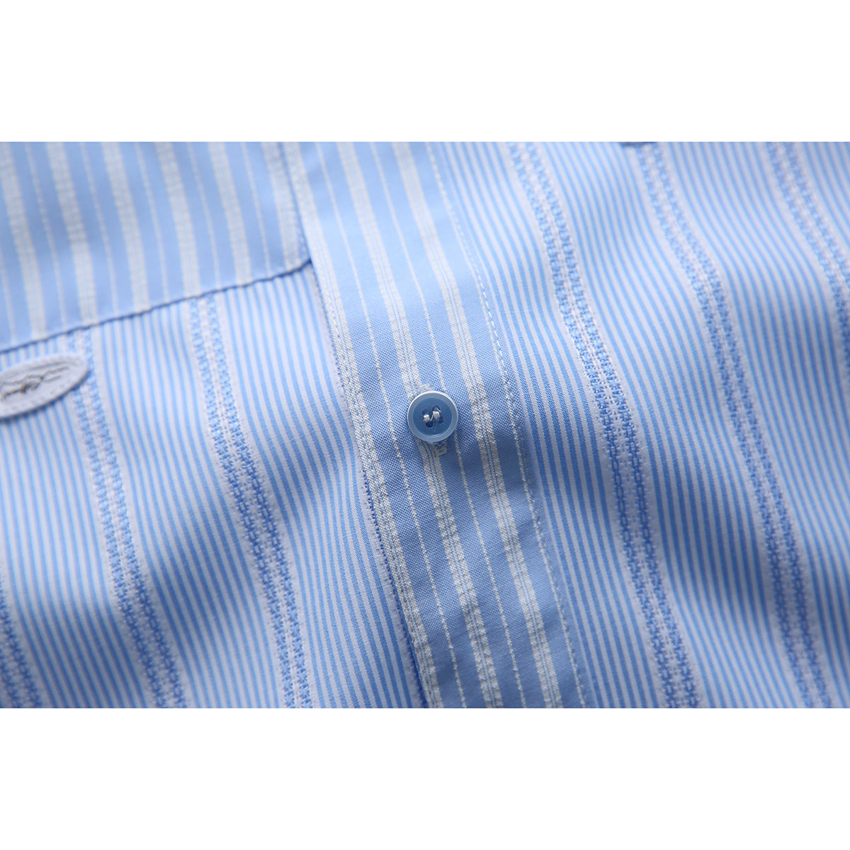 Close-up of the light blue shirt's striped fabric, button placket, and blue button.