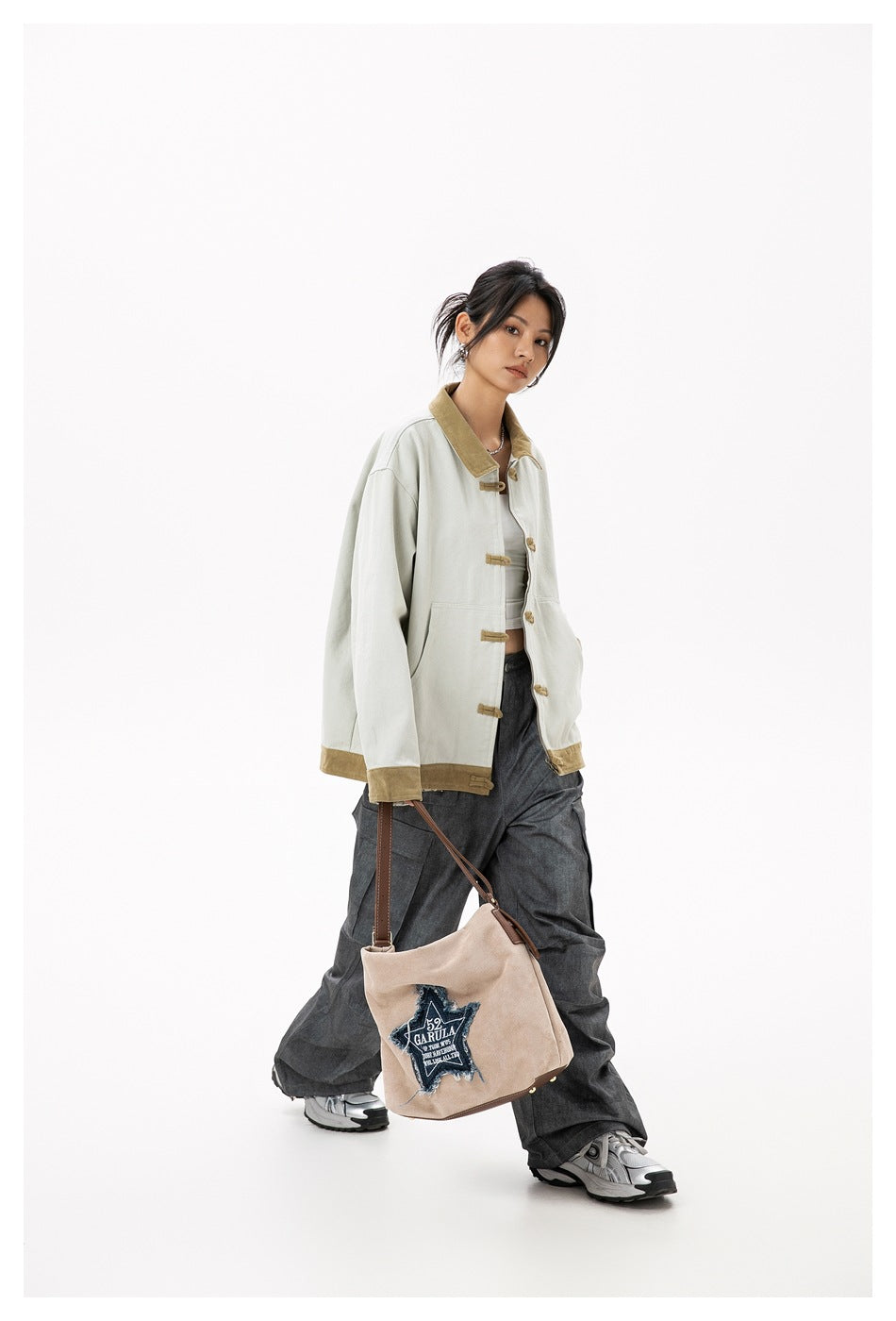 Model wearing a pale gray jacket with tan corduroy collar, cuffs and frog closures, styled with dark trousers.
