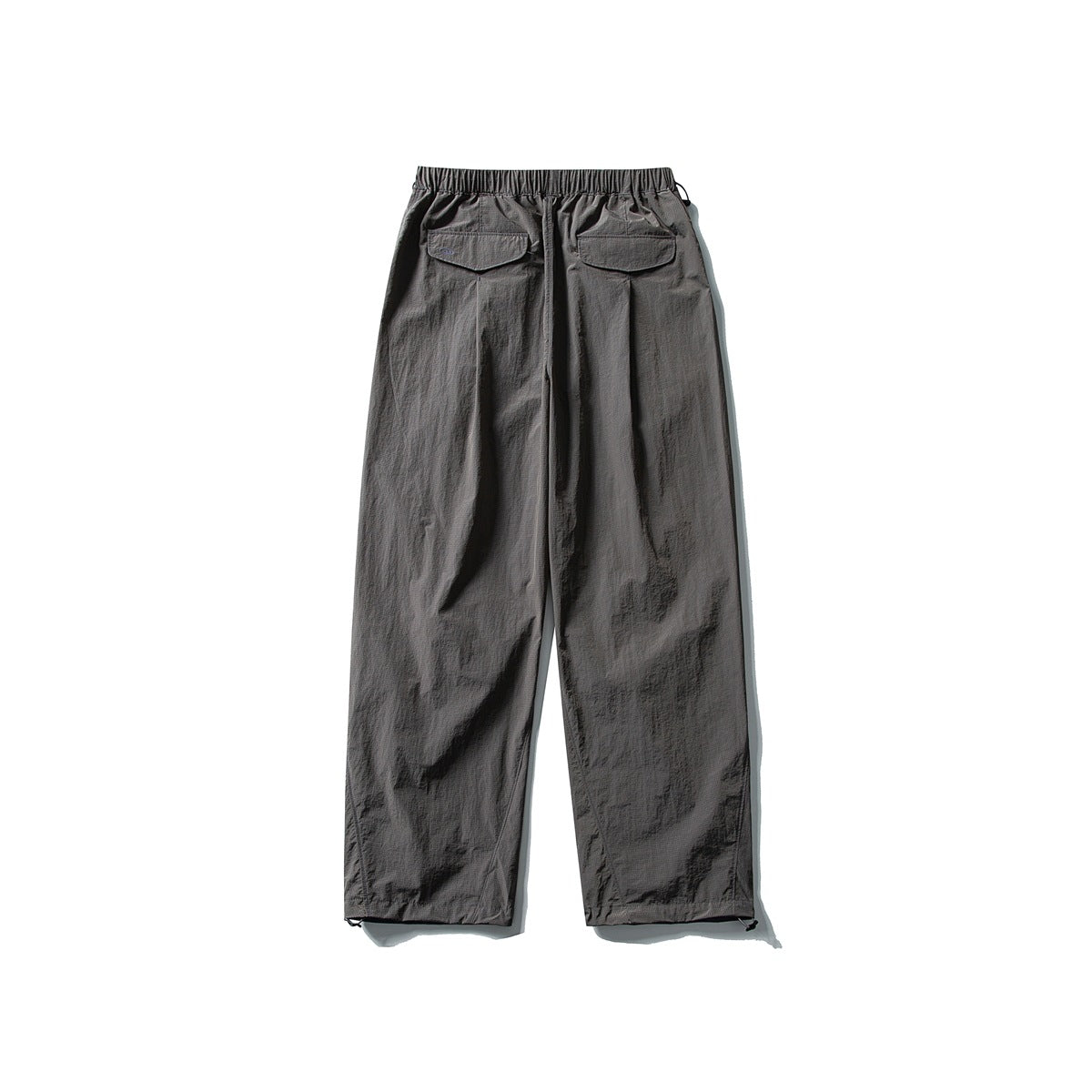 Back view of charcoal gray loose-fitting pants with an elastic waist and two flap pockets, displayed flat on white.