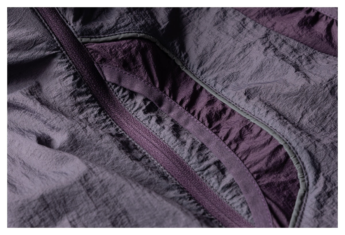 Close-up of dark gray and purple jacket panels, curved seam binding, and a dark zipper.