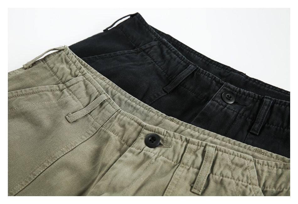 Close-up of black and olive trousers overlapping, showing waistbands, buttons, belt loops and pocket details.