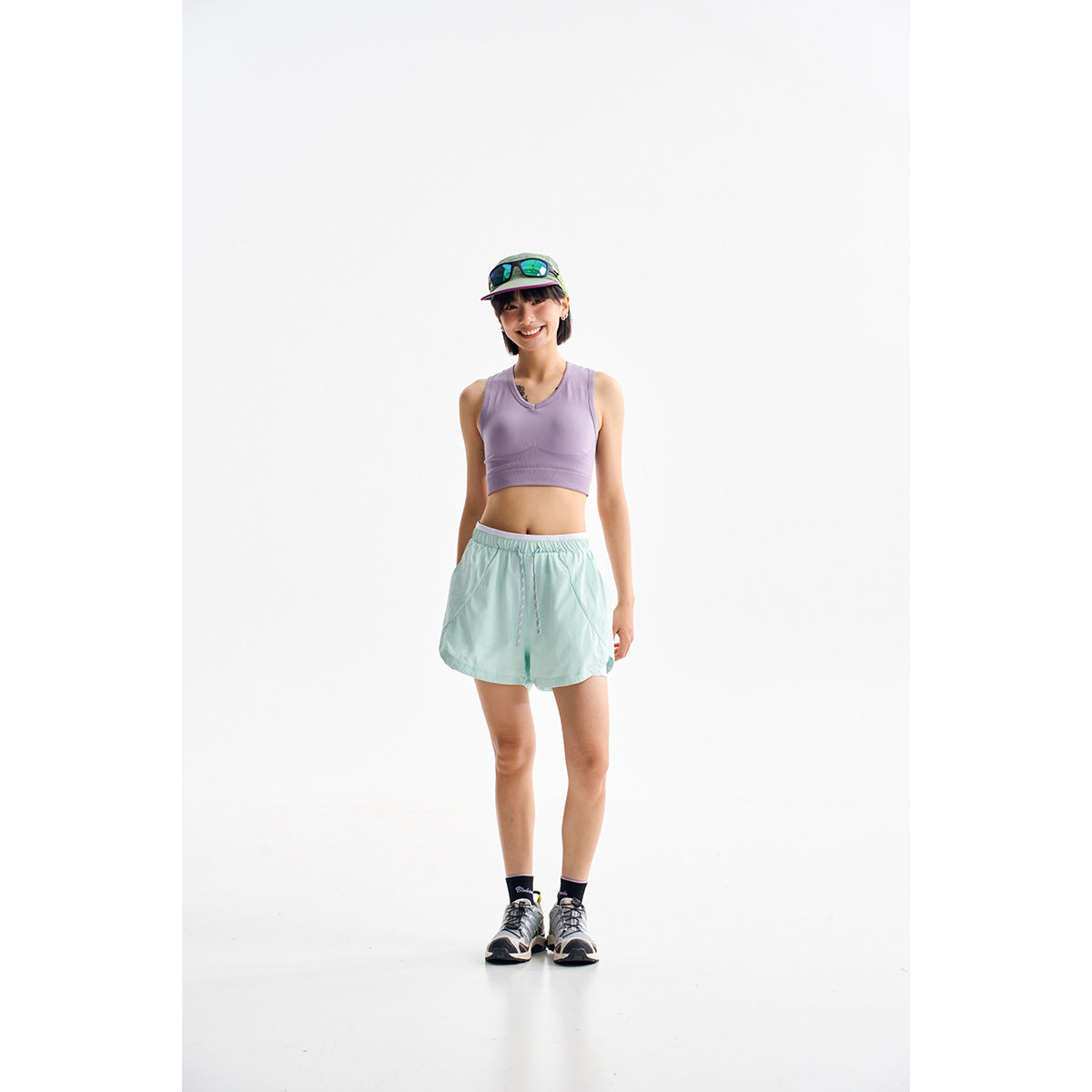 Model wearing a lavender cropped tank and mint-green loose drawstring athletic shorts.