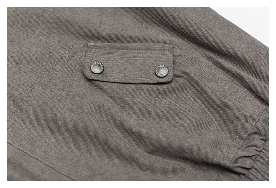 Close-up of a charcoal gray flap pocket secured with two round snap buttons.
