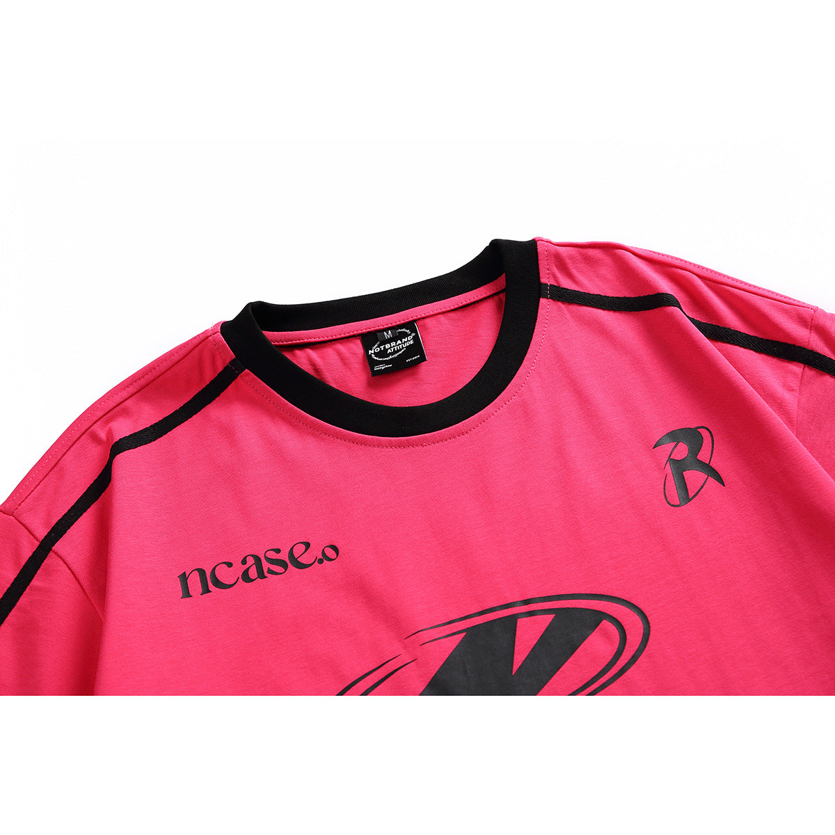 Close-up of a bright pink T-shirt front with a black crew neck, shoulder stripes, and black printed graphics.