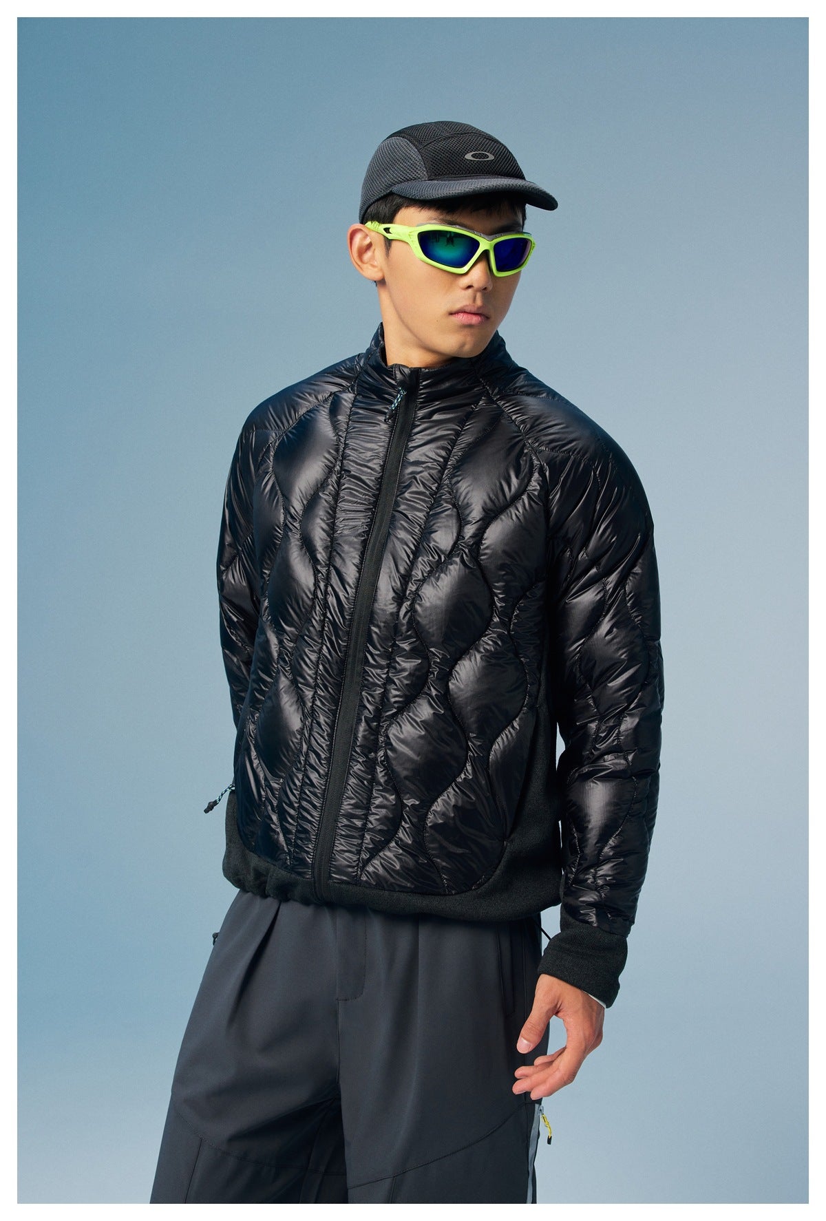 Three-quarter view of a man wearing a glossy black quilted zip jacket with a high collar.