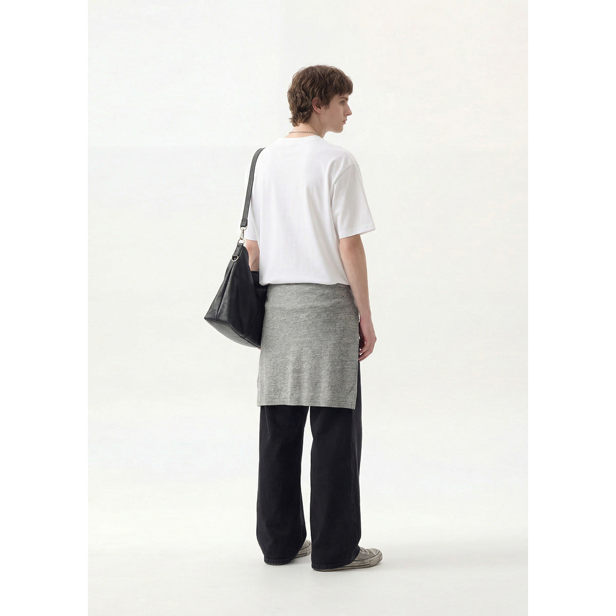 Rear view of a model wearing a plain white crew-neck T-shirt and loose black trousers.