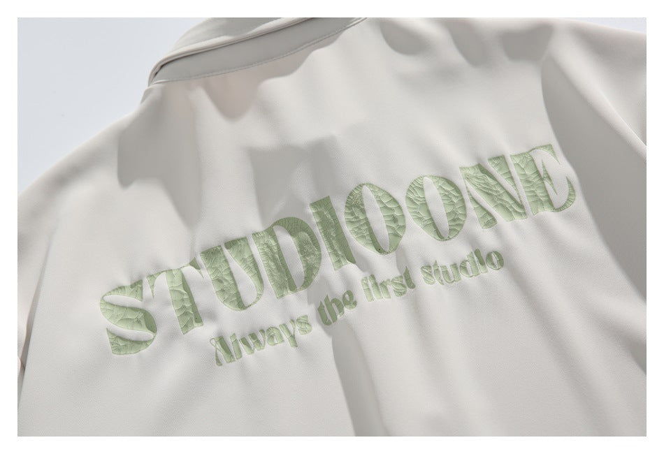 Close-up of pale green textured lettering on the back of an off-white garment.