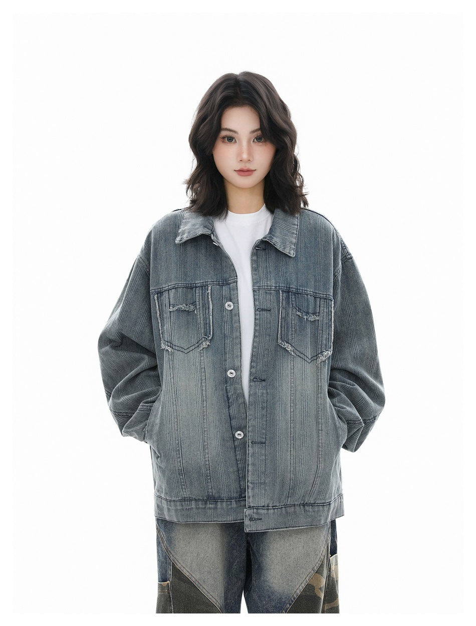 Model wearing a blue washed striped denim jacket open over a white tee, hands in pockets, with camouflage-panel jeans