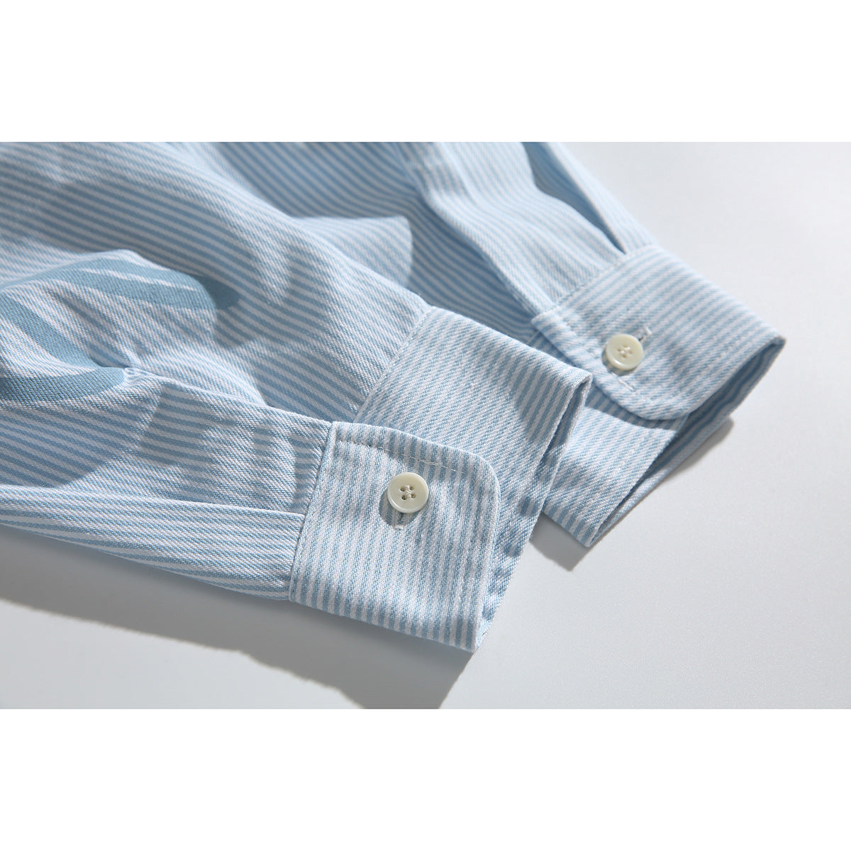 Close-up of pale blue striped shirt sleeves and buttoned cuffs.