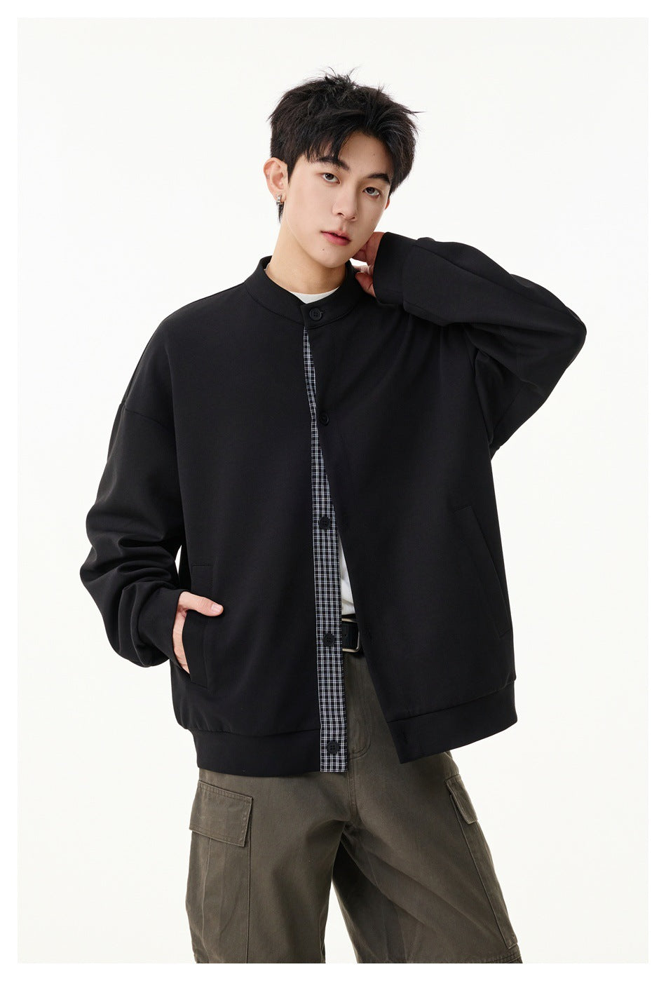 Model poses in a black button-front jacket with a checked placket and angled side pockets.