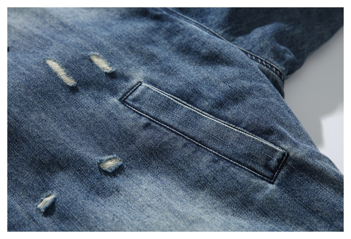 Close-up of a blue denim jacket pocket and several small distressed rips.