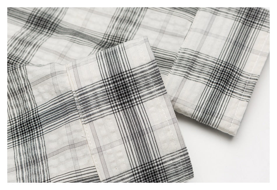 Close-up of a black-and-white plaid shirt cuff and sleeve, showing the patterned fabric and stitching.