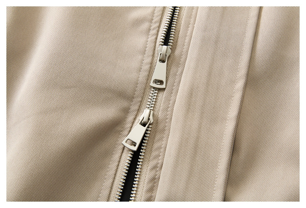 Close-up of a beige jacket's metal front zipper with two sliders.