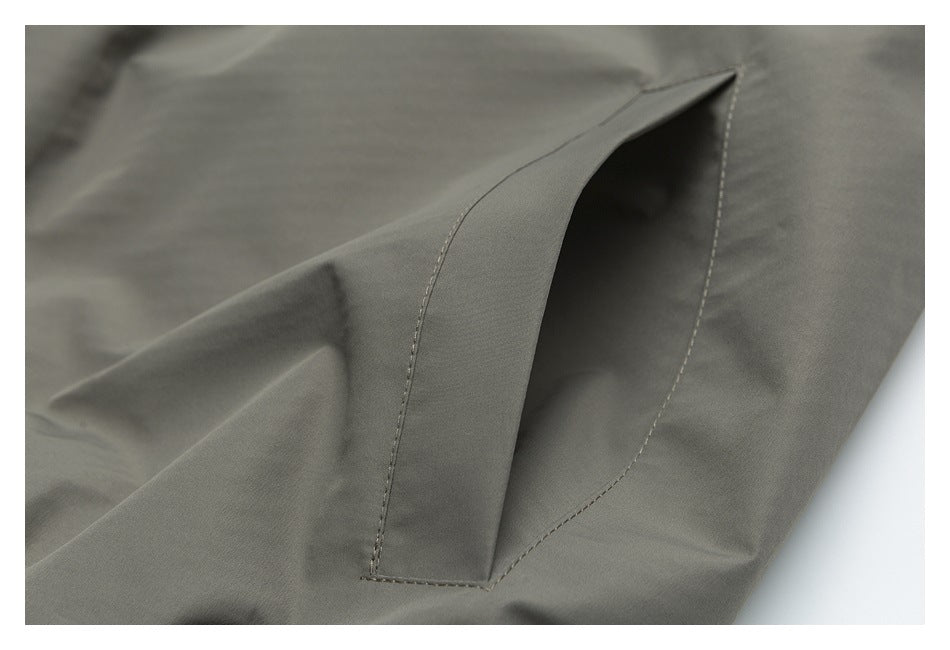 Close-up of an angled welt pocket and stitching on olive-gray fabric.
