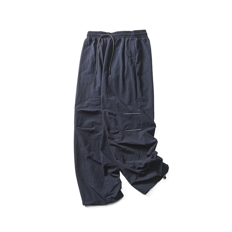 Dark navy loose-fit pants laid flat, with an elastic drawstring waist, side pockets and wide legs.