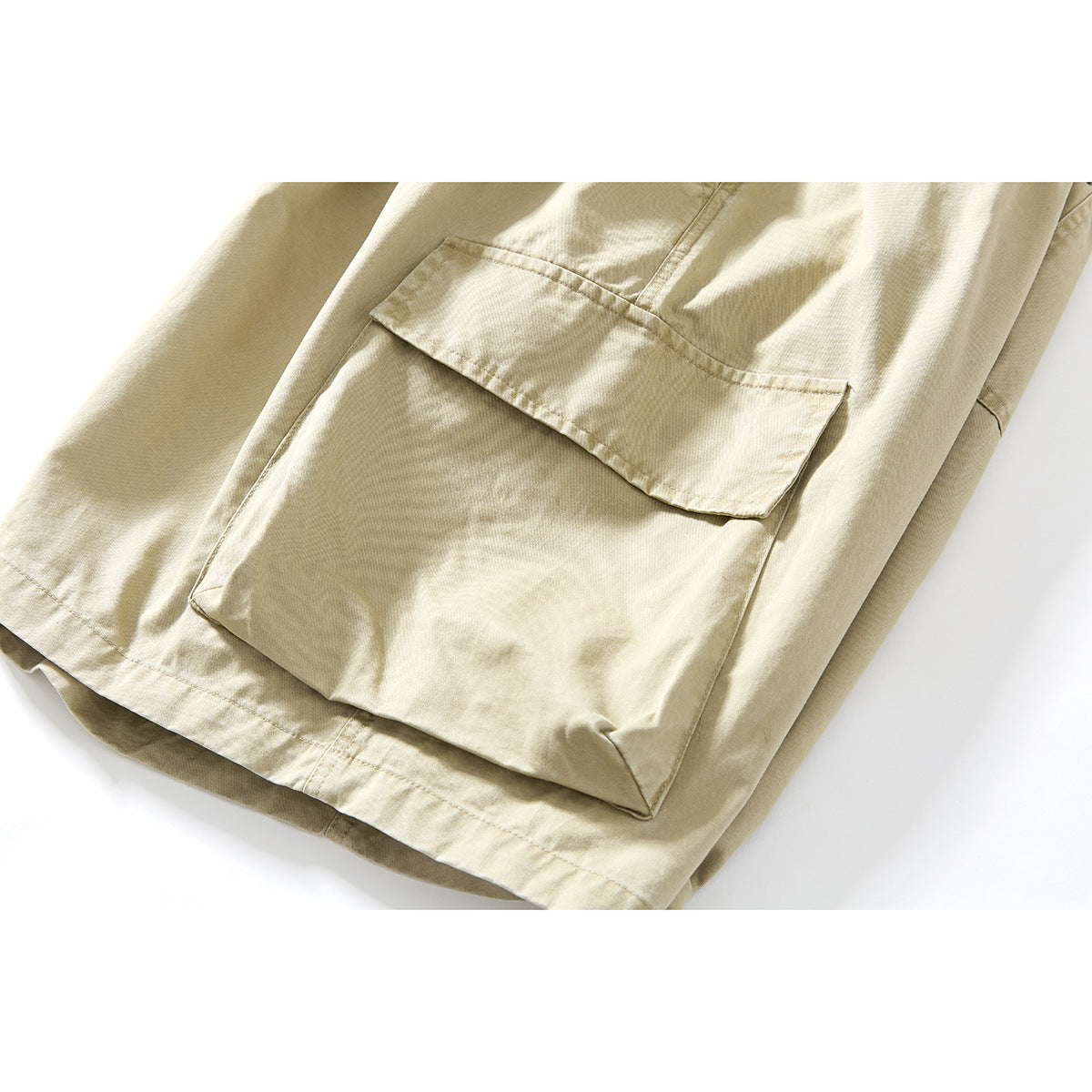 Close-up of a large flap cargo pocket on beige shorts.