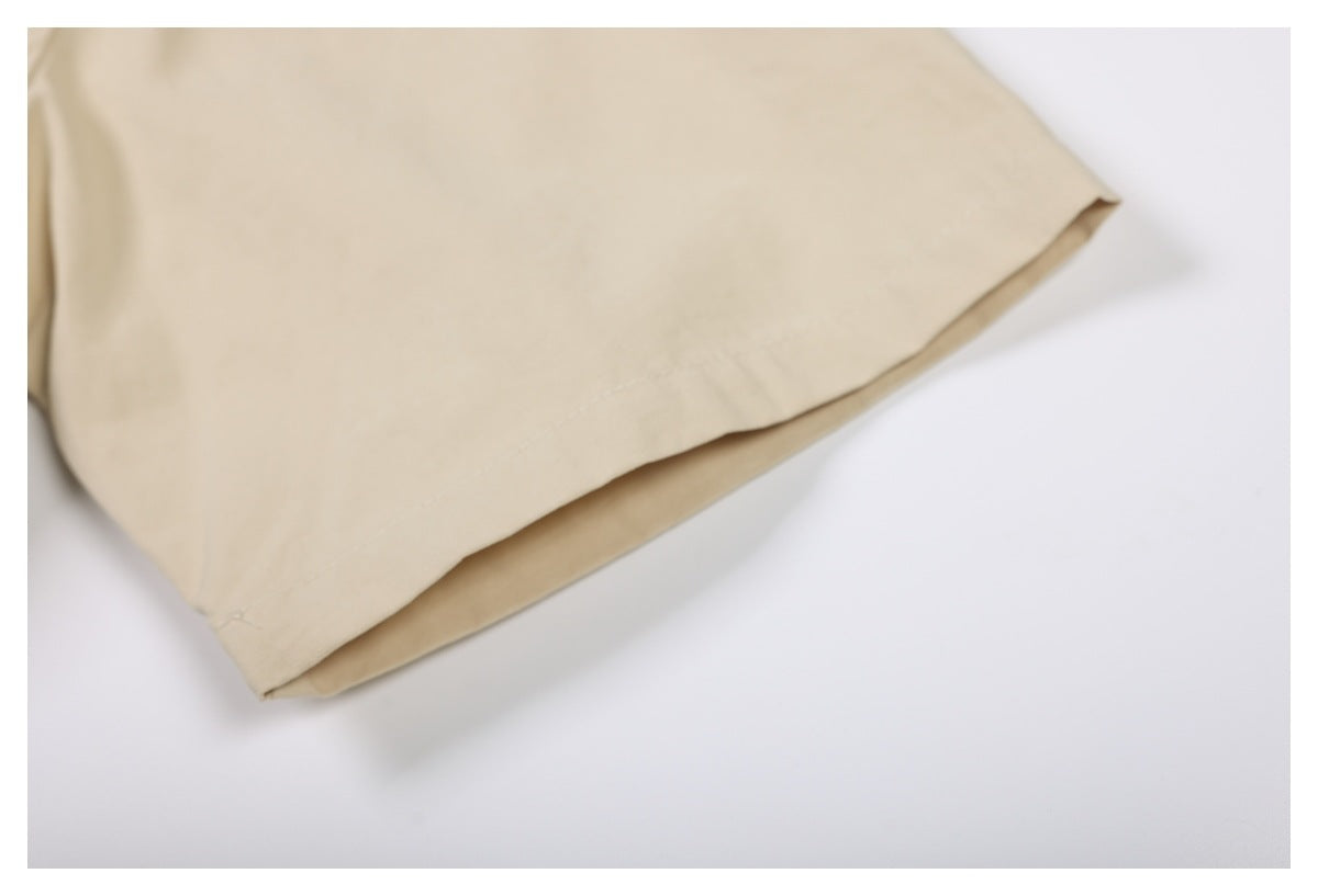 Close-up of the stitched hem on a plain beige shirt sleeve.