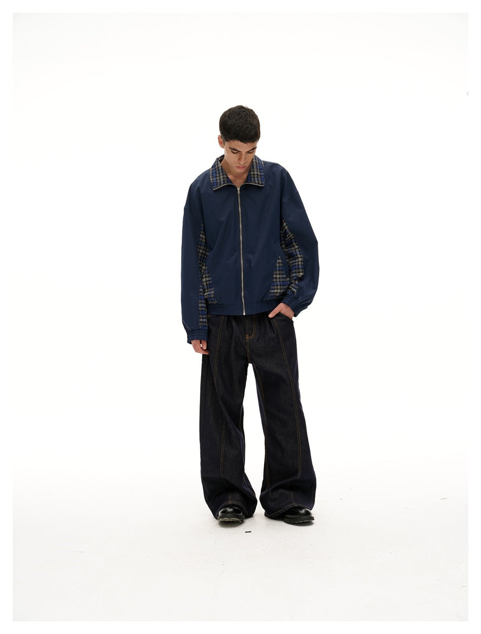 Full-length view of a model looking down in a navy zip-front jacket with plaid collar and side panels.