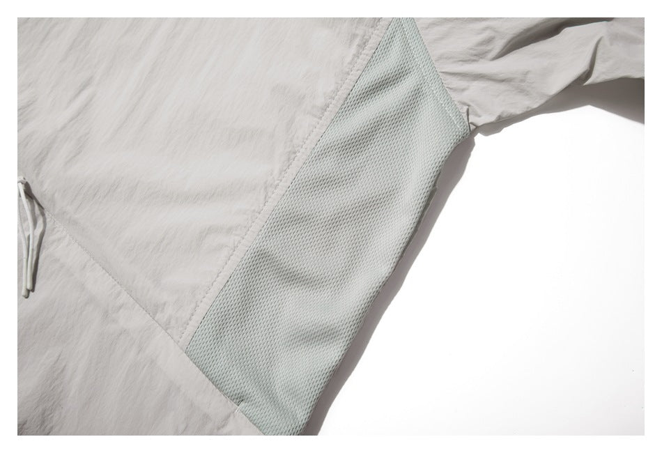 Close-up of a pale mesh underarm panel on the light gray jacket.