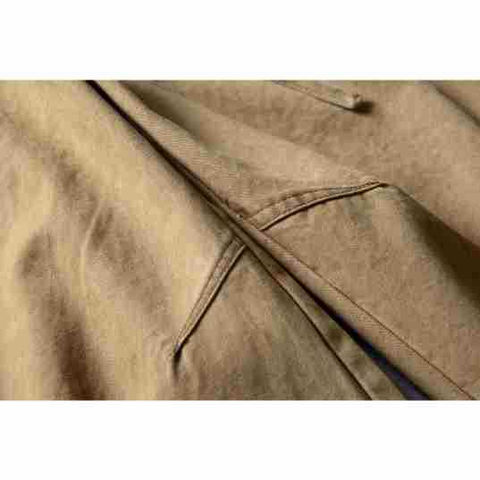 Close-up of tan shorts showing the front pocket opening and button-fly area.