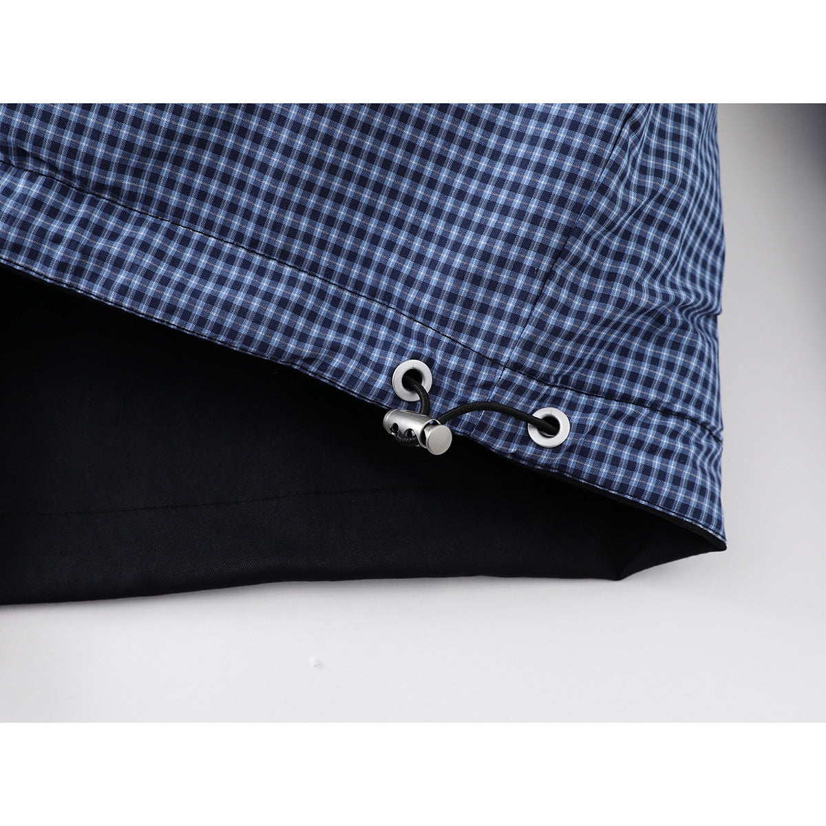Close-up of the jacket's blue check-patterned lower panel and adjustable black drawcord with metal eyelets.