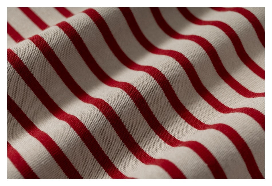 Close-up of cream fabric with red stripes draped in soft folds.