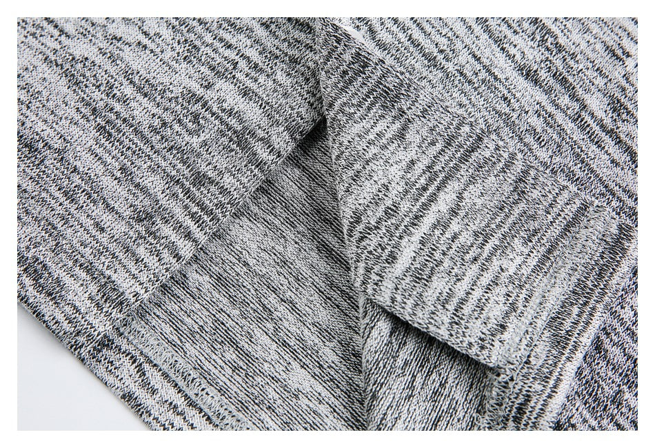 Inside view of a black, gray, and white marled knit garment, showing a folded seam and overlock stitching.