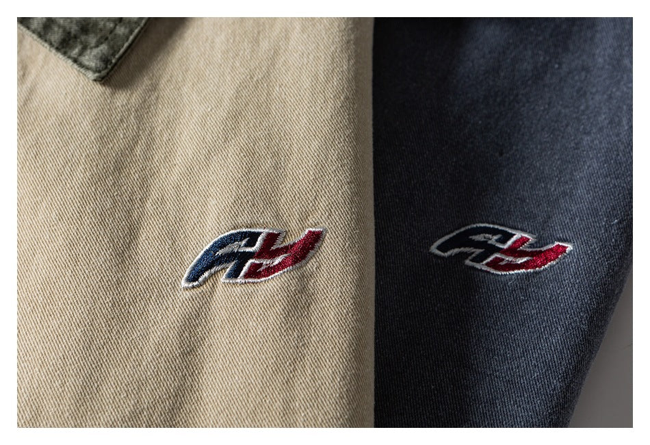 Close-up of a red, white, and navy embroidered emblem on beige and dark blue jacket fabric.