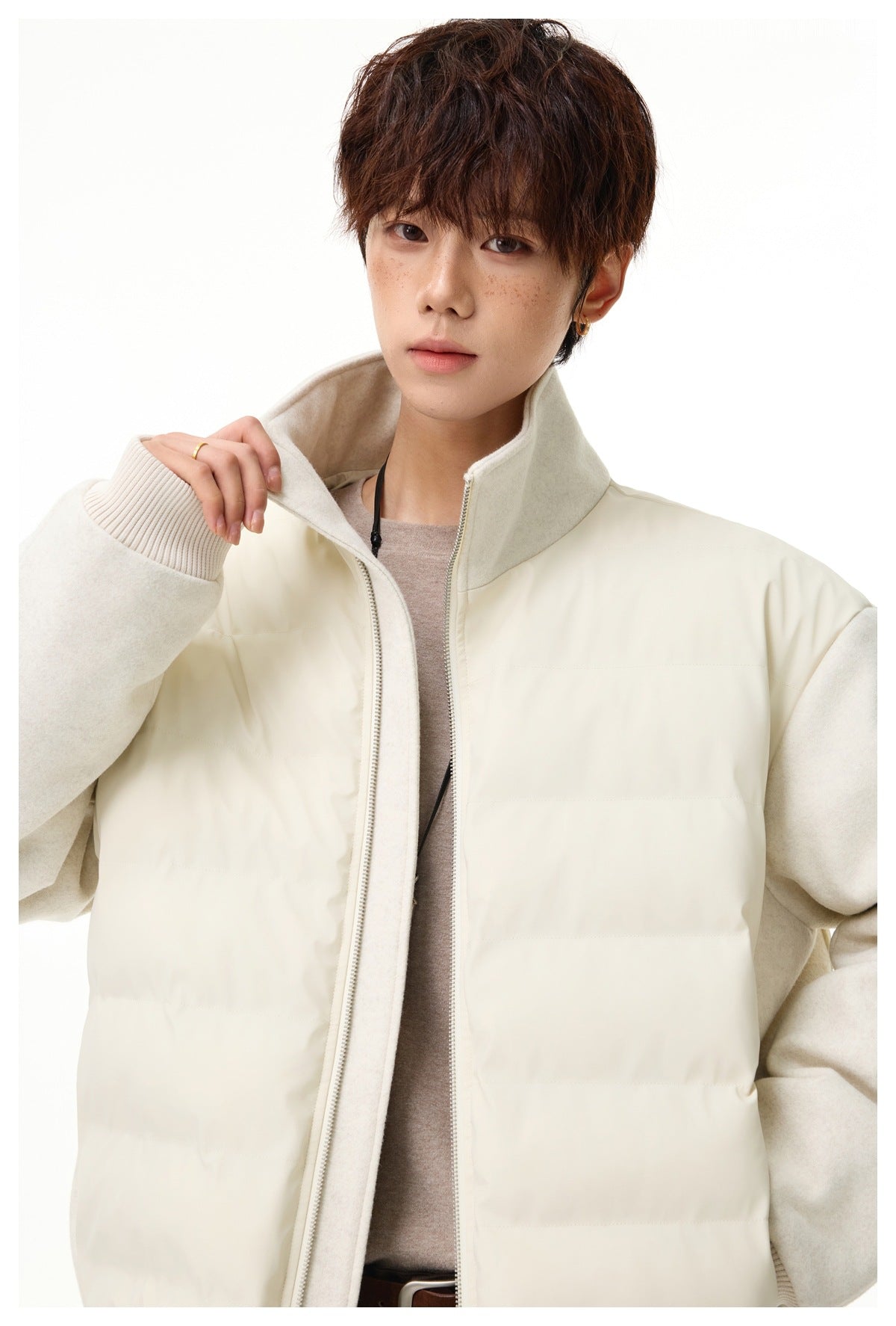 Close view of the ivory jacket’s quilted front, textured sleeve, ribbed cuff, high collar, and zipper.