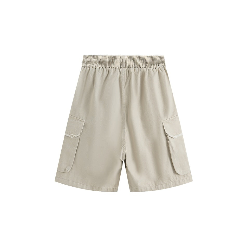 Back view of beige cargo shorts with an elastic waistband and two large side pockets with frayed flaps.