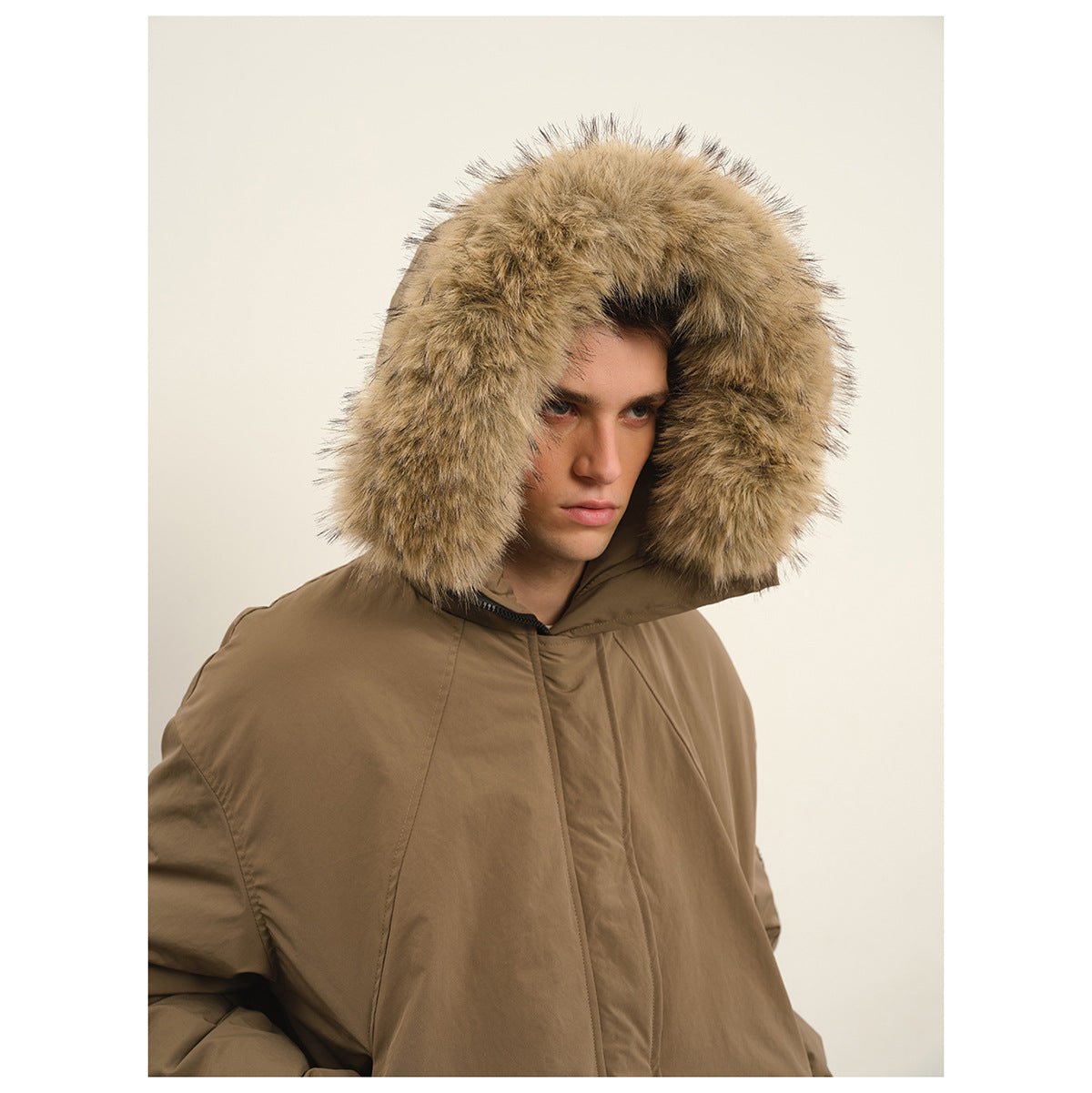 Close-up of a man wearing a taupe hooded jacket with a large tan fur-trimmed hood.