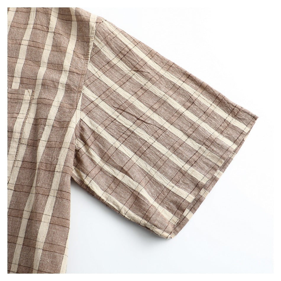 Close-up of the brown and cream plaid shirt's short sleeve and stitched hem.