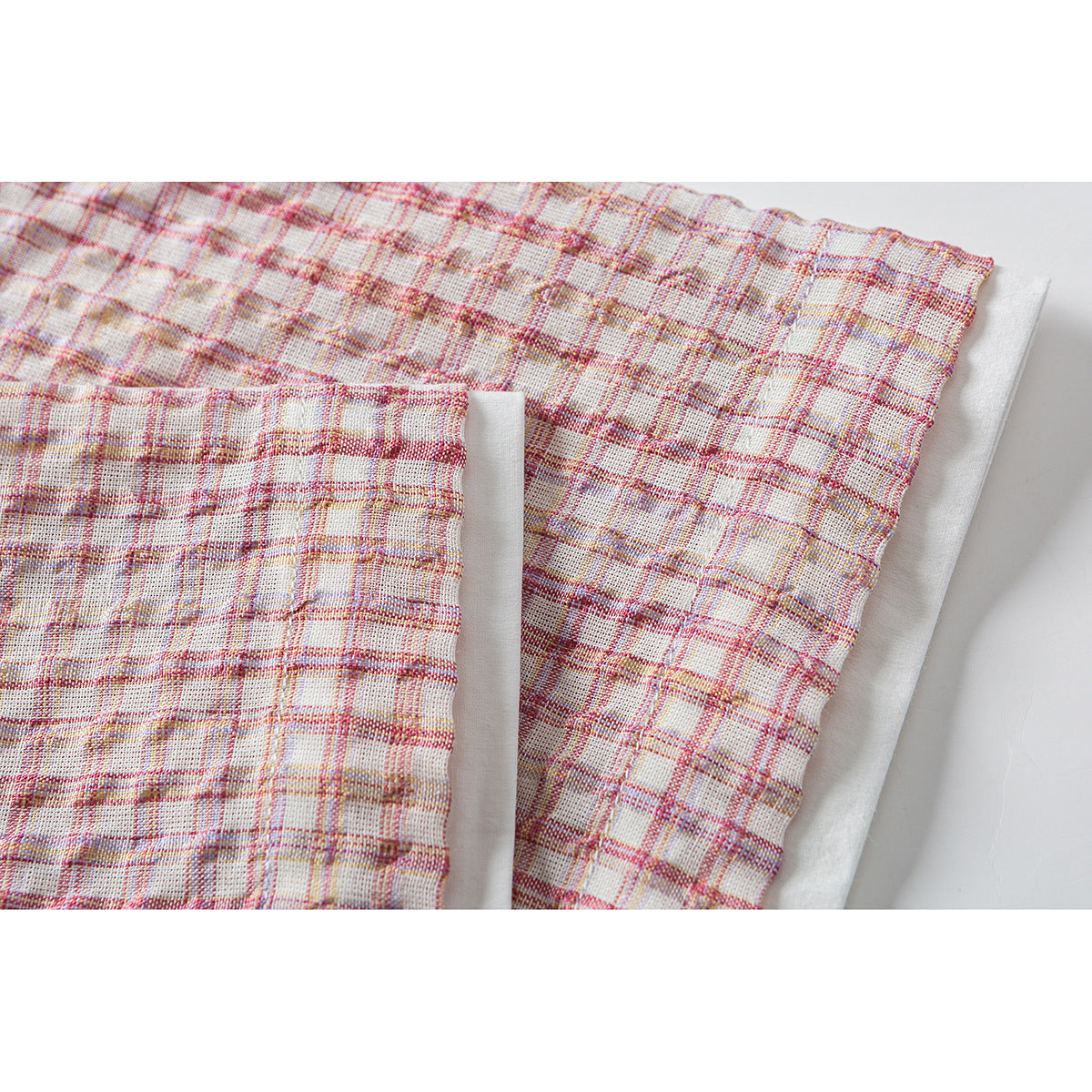 Close-up of the pink plaid garment showing a gathered edge and layered seam.