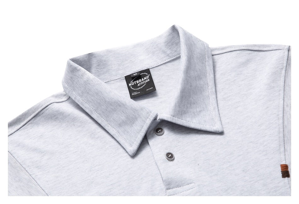 Close-up of a light gray polo shirt collar, button placket, sewn-in neck label, and brown embroidered detail.