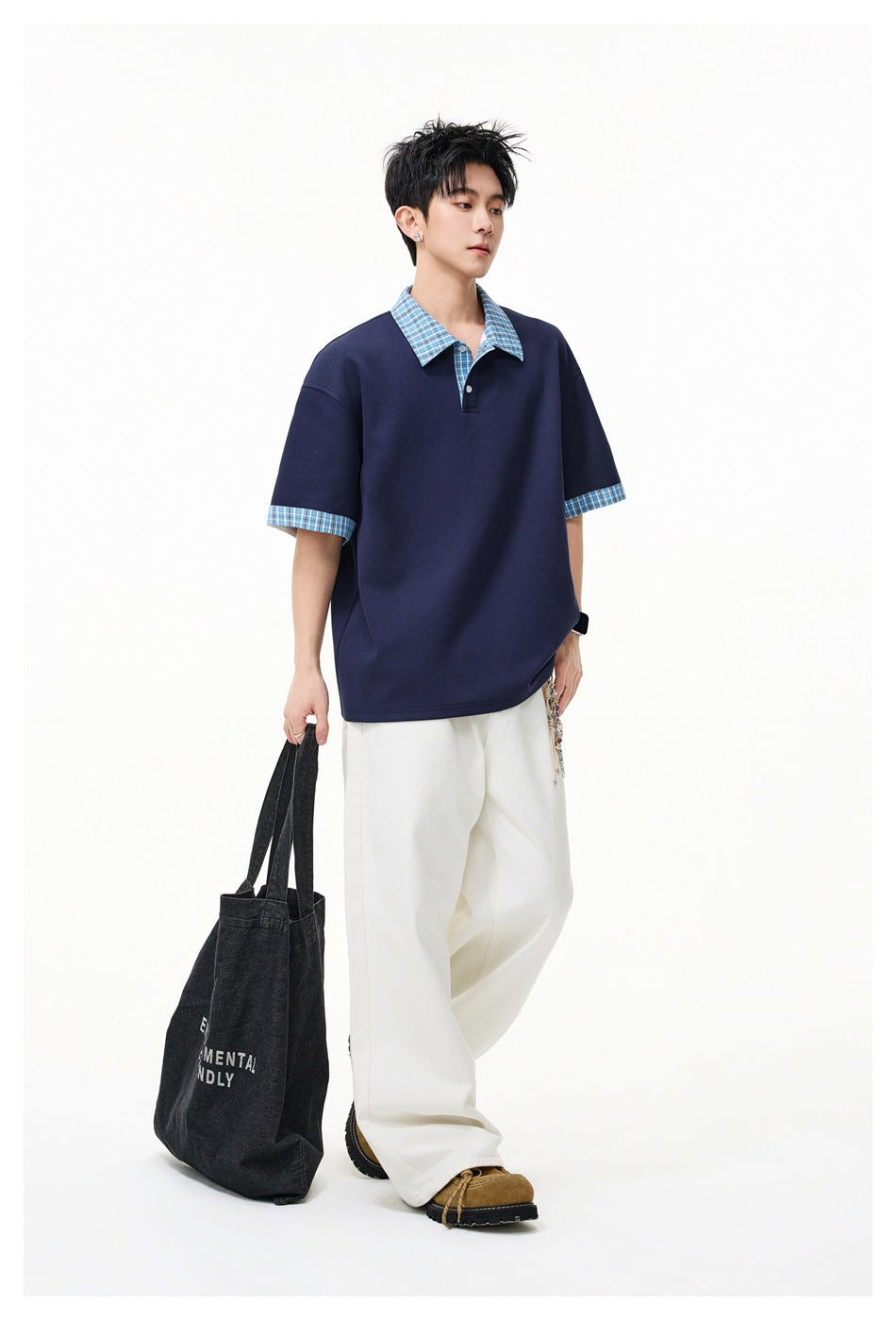 Model wearing a loose navy polo with a blue checked collar and sleeve cuffs, paired with wide white trousers.