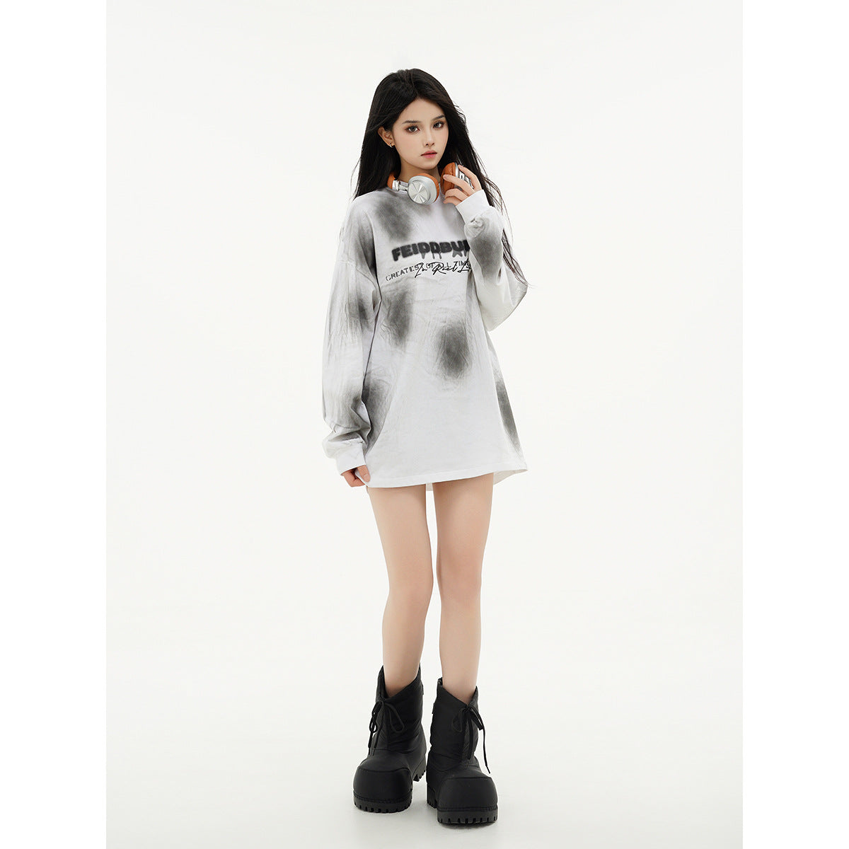 Model wearing an oversized white and gray tie-dye long-sleeve shirt with black chest lettering and black platform boots.