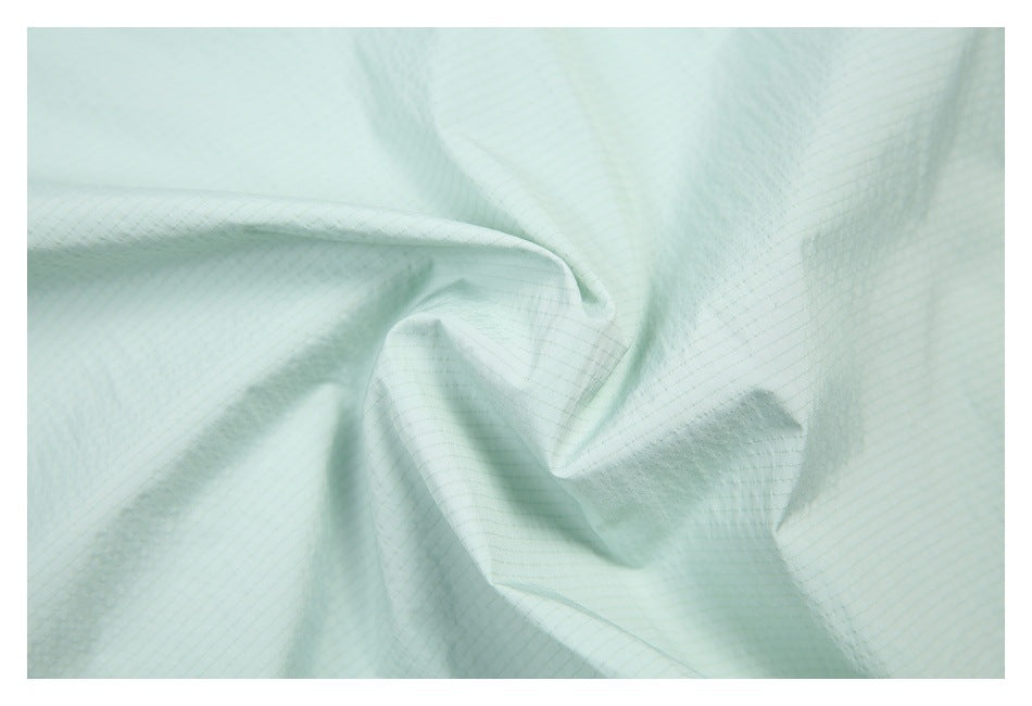 Close-up showing the fine grid texture of pale mint garment fabric.