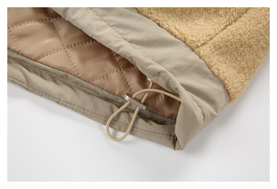 Close-up of a beige coat hem showing quilted lining, a drawcord loop, and a metal toggle.