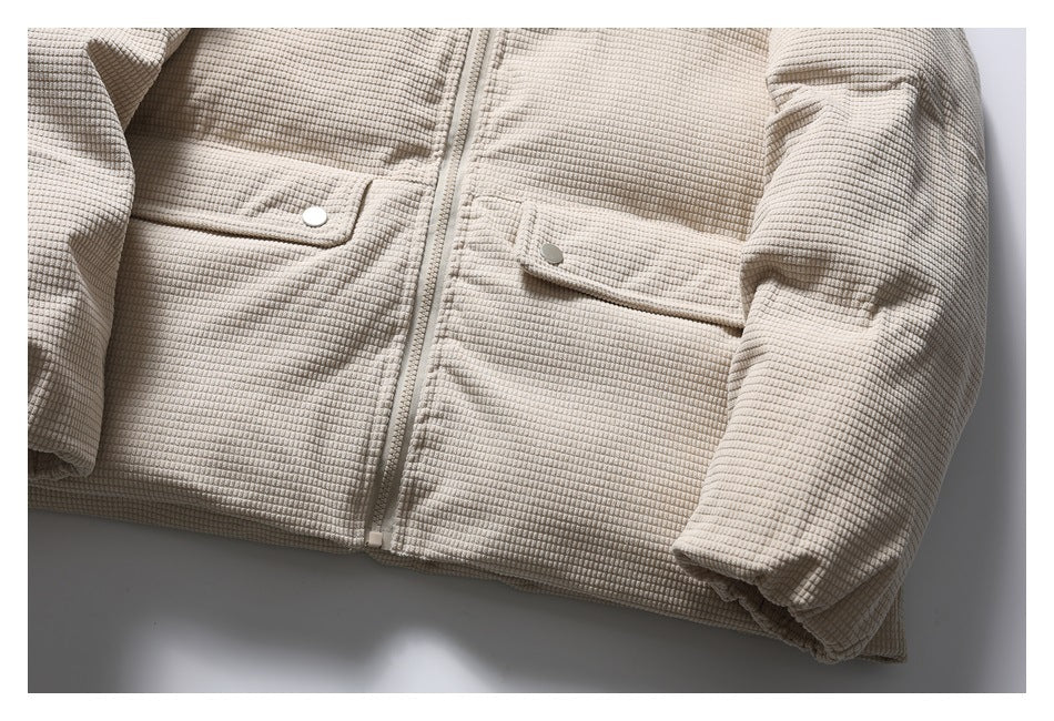 Cropped lower front of a light beige textured jacket, showing its zipper and two snap-button flap pockets.