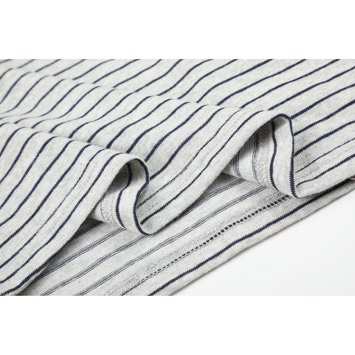 Close-up of the striped shirt's folded hem and overlock stitching.